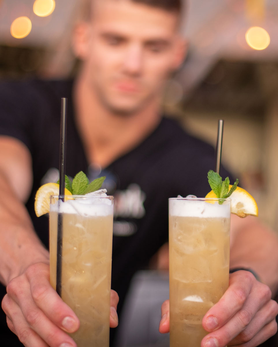 A bartender hands over two cocktails